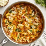 Overhead view of cheese tortellini and sausage skillet with garlic bread and parsley on the side.