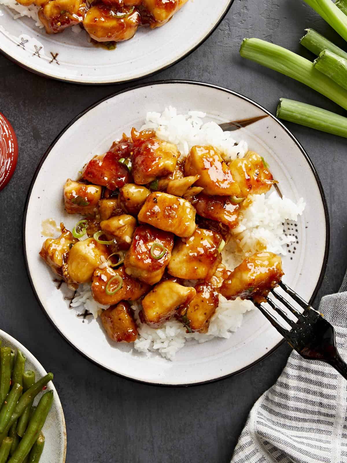 Overhead view of honey garlic chicken on a plate with white rice and a black fork.