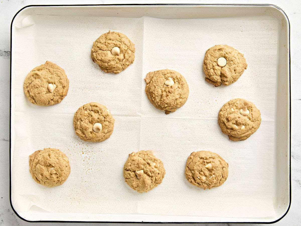 Freshly baked pumpkin cookies on a parchment lined baking sheet.