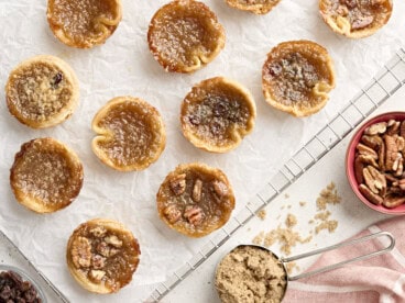 Overhead view of butter tarts on a parchment lined cooling wrack.