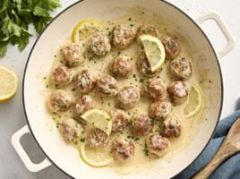 Overhead view of Chicken meatballs in a large skillet with a lemon cream sauce.