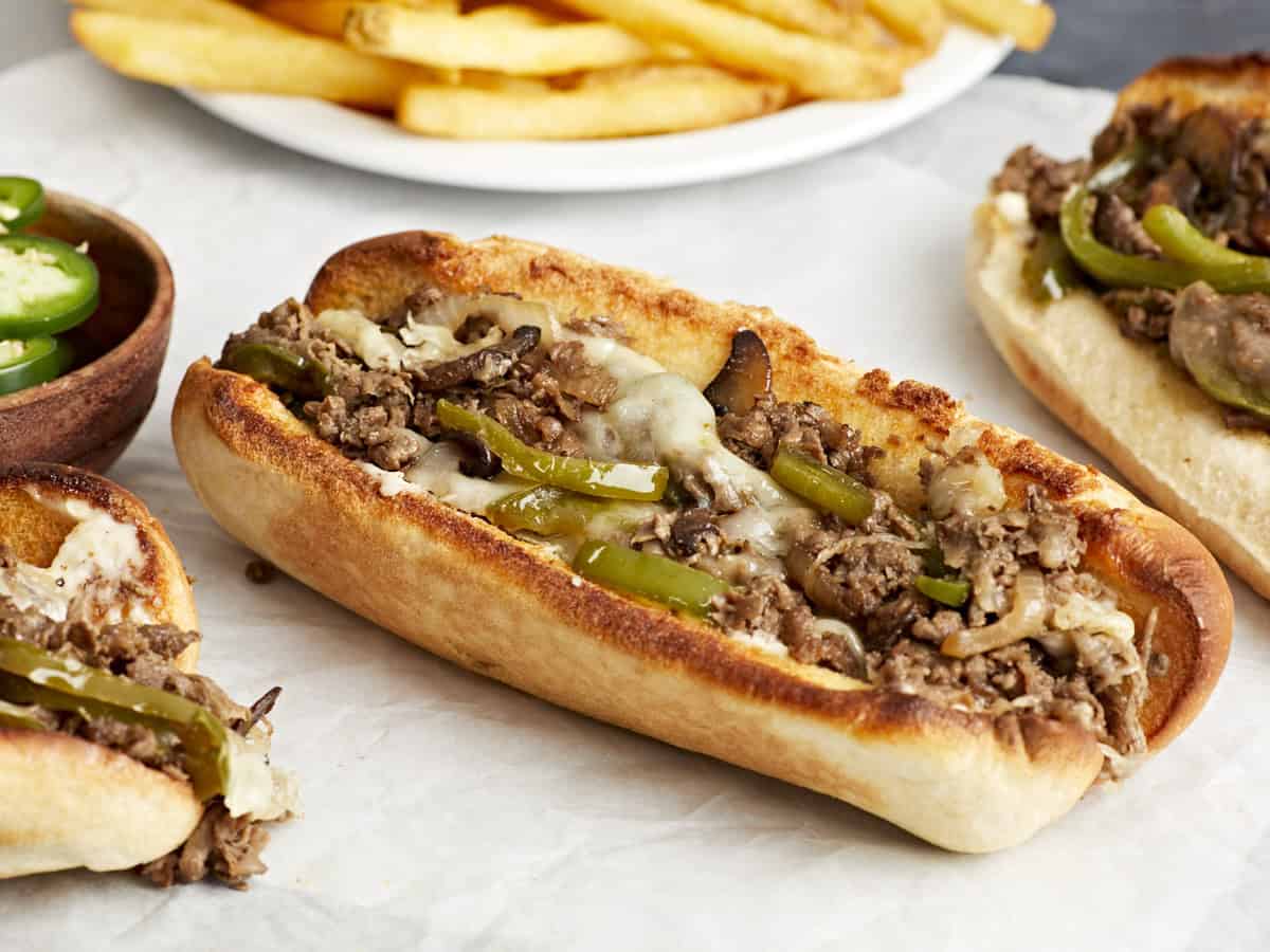 Side close up view of a philly cheesesteak on parchment paper.