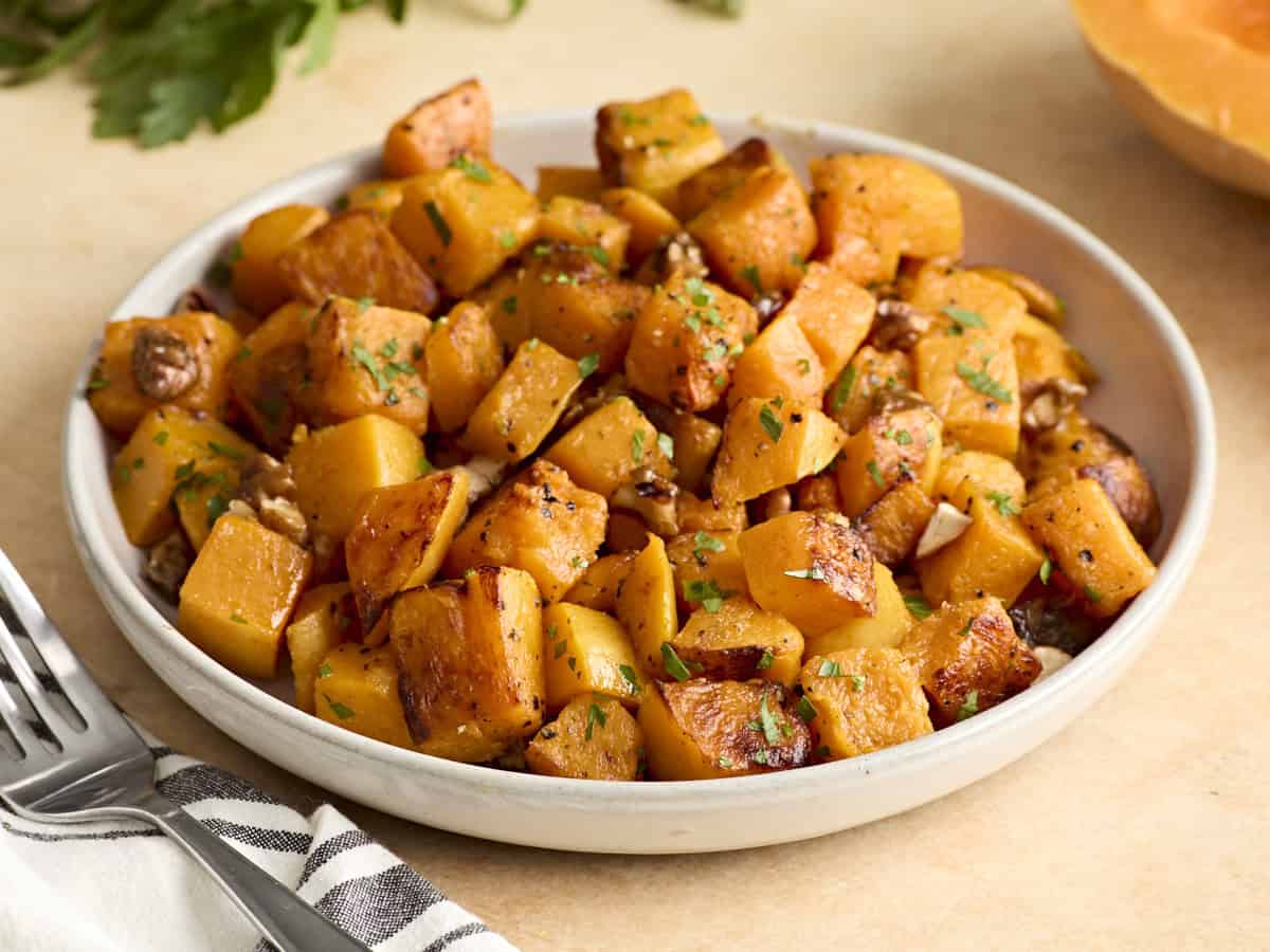 Side view of a bowl of roasted butternut squash cubes.