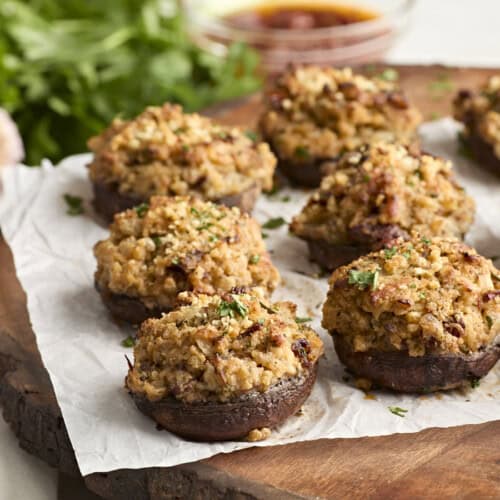 Side view of stuffed mushrooms on a wooden chopping board.