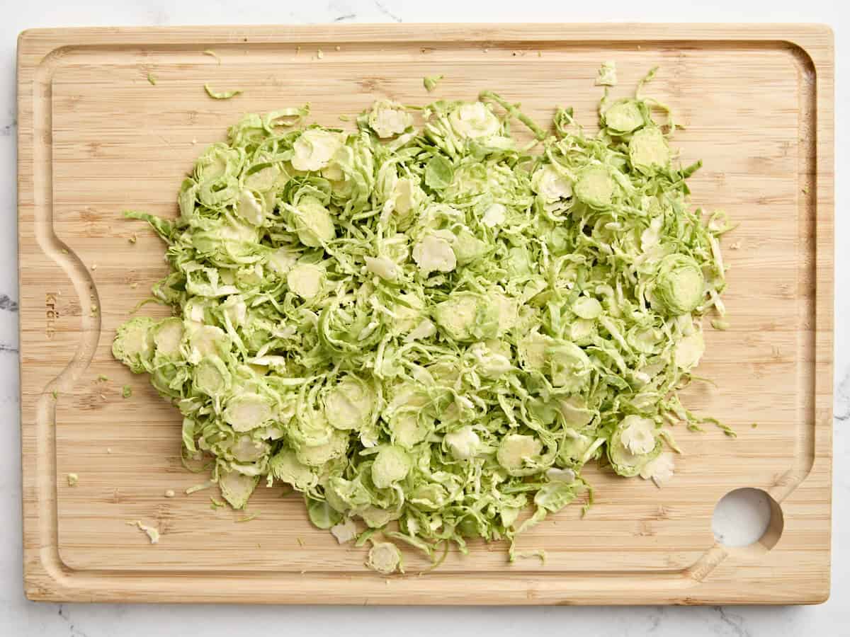 Shaved Brussels sprouts on a wooden chopping board.