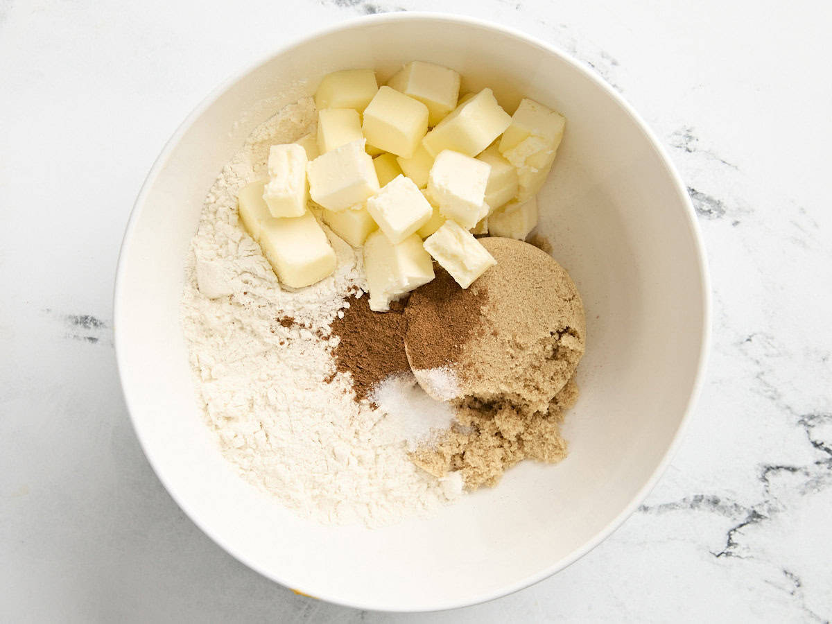 Cubed butter, flour, sugar, and pumpkin pie spice in a mixing bowl.