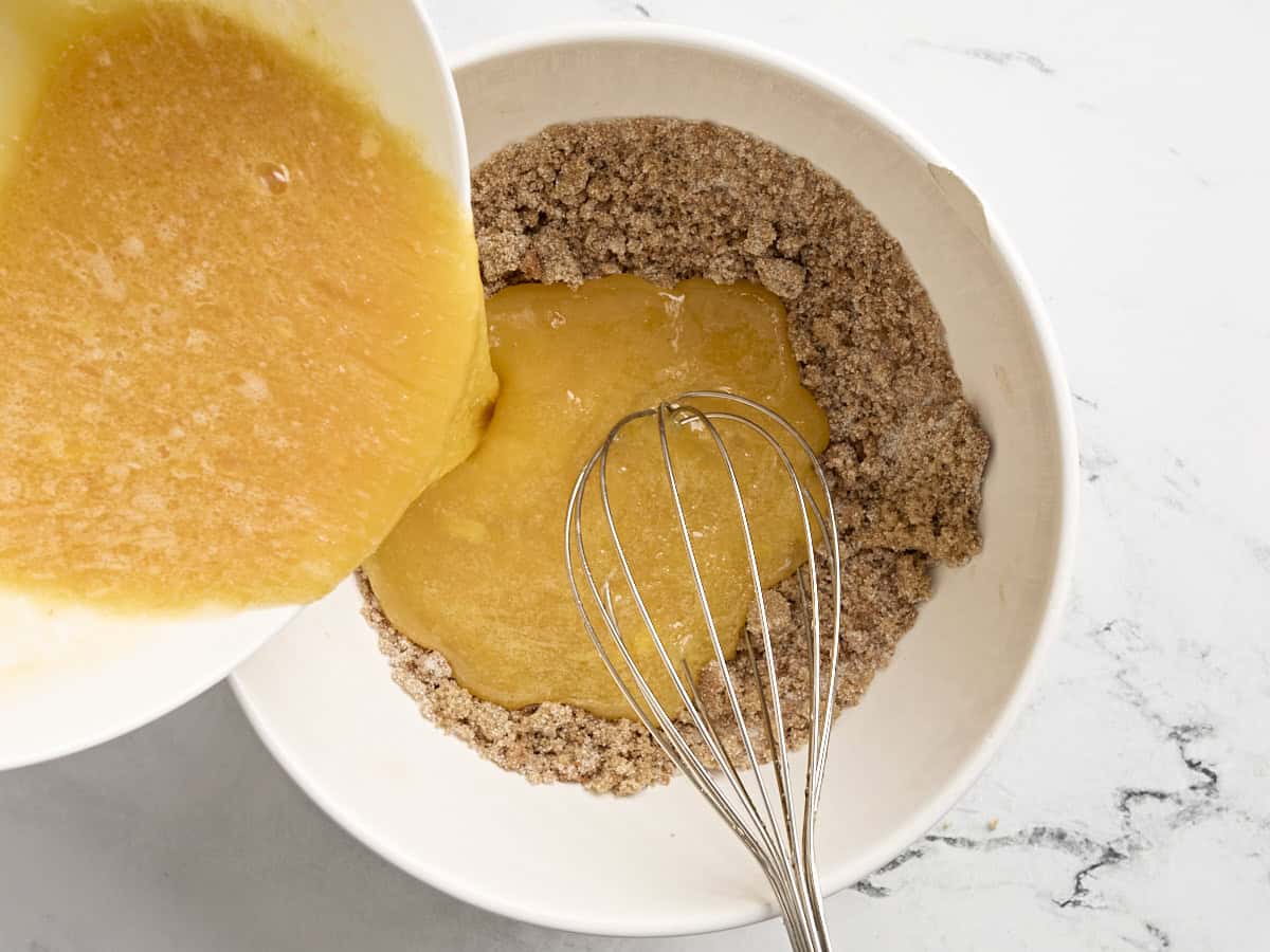 Wet ingredients being poured into dry ingredients in a mixing bowl for pecan pie.