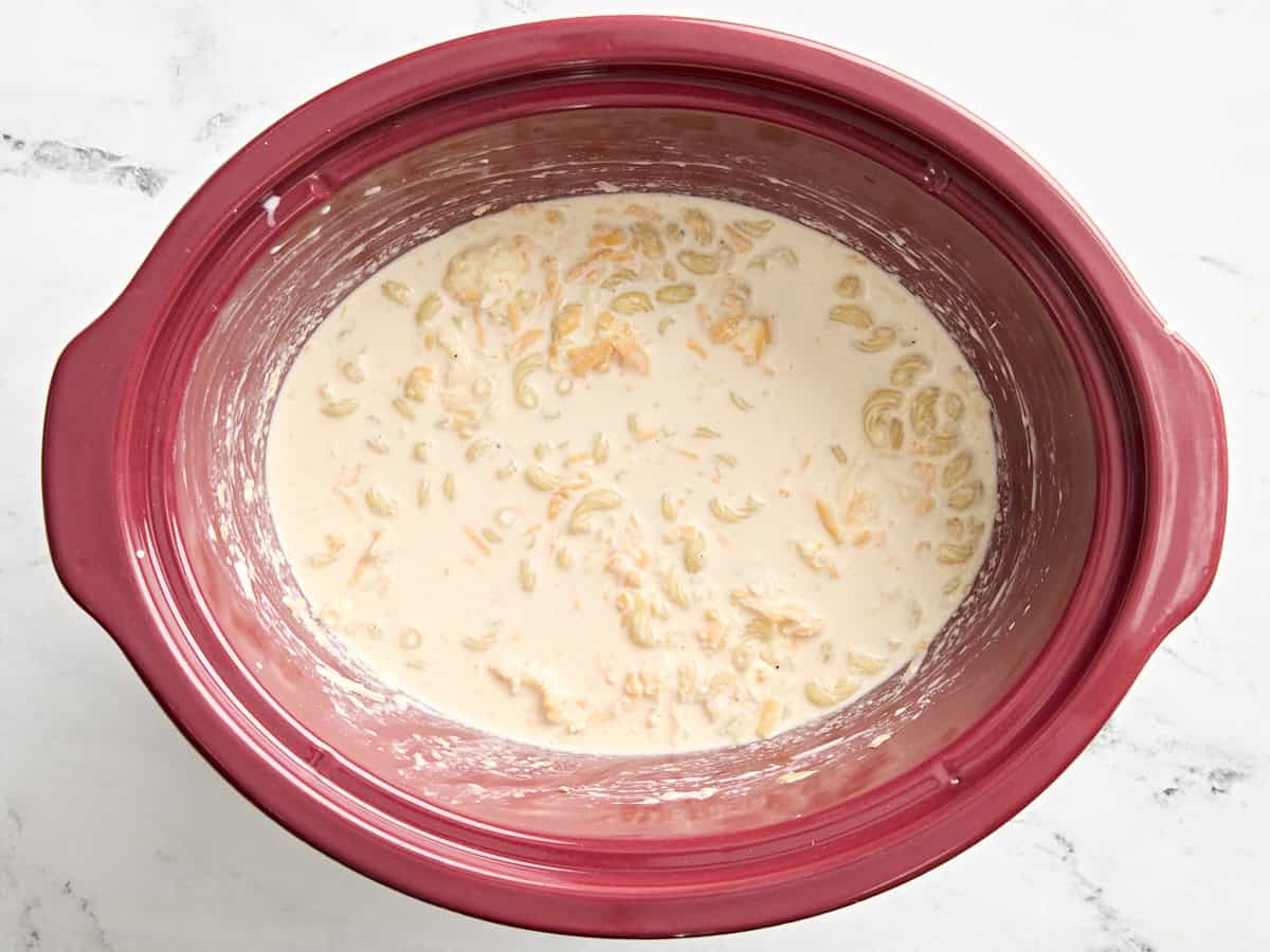 Mac and cheese ingredients stirred together in a crock pot.