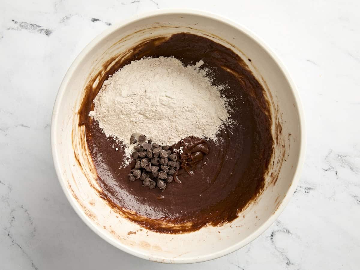 Dry ingredients and chocolate chips added to the wet chocolate mixture in a mixing bowl.