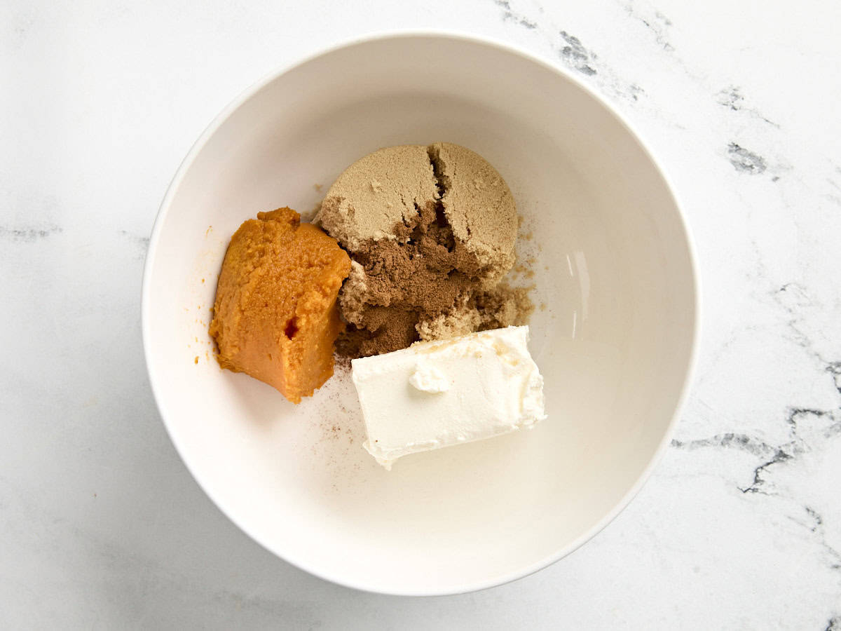 Sugar, pumpkin puree, and cream cheese in a mixing bowl.