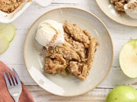 Overhead view of apple crumble on a plate with a scoop of vanilla ice cream.