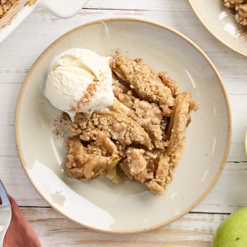 Overhead view of apple crumble on a plate with a scoop of vanilla ice cream.