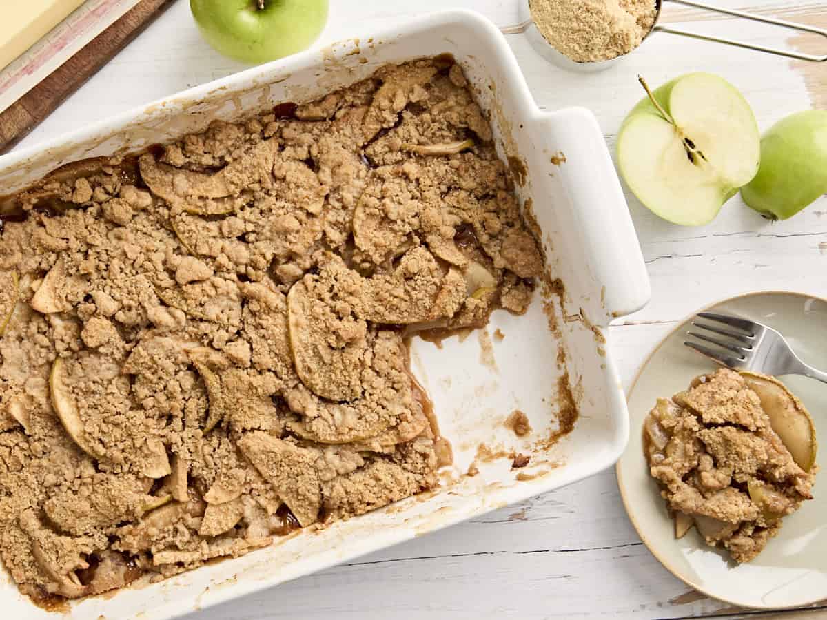 Overhead view of apple crumble in a rectangular baking dish with a portion missing.