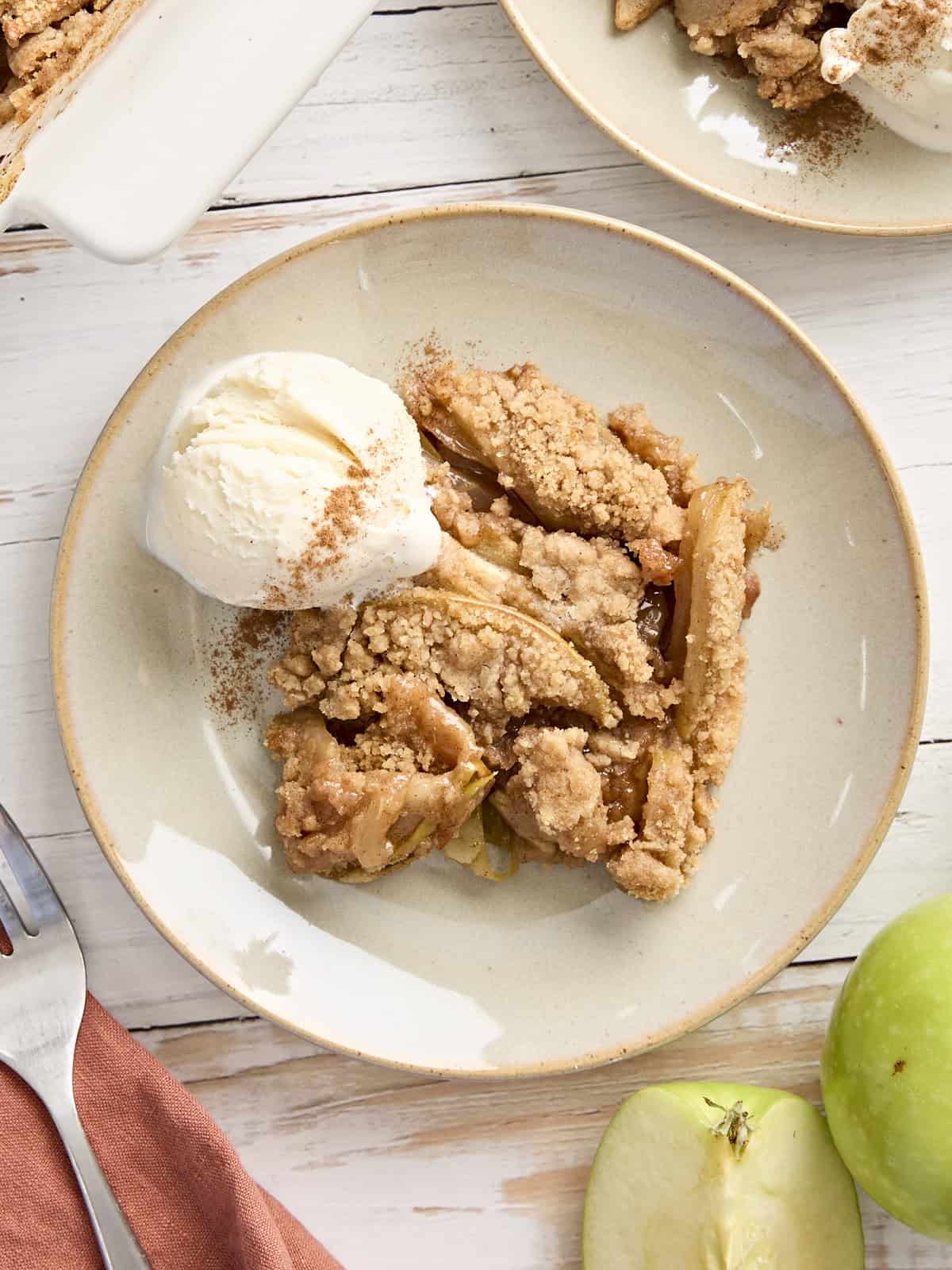 Overhead view of apple crumble on a plate with a scoop of vanilla ice cream.