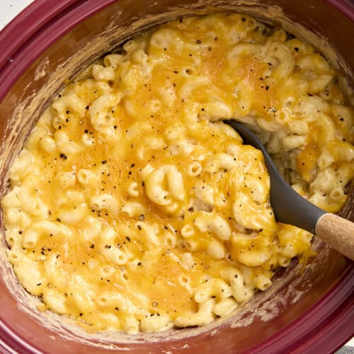 Overhead view of crock pot mac and cheese with a large spoon lifting some out.