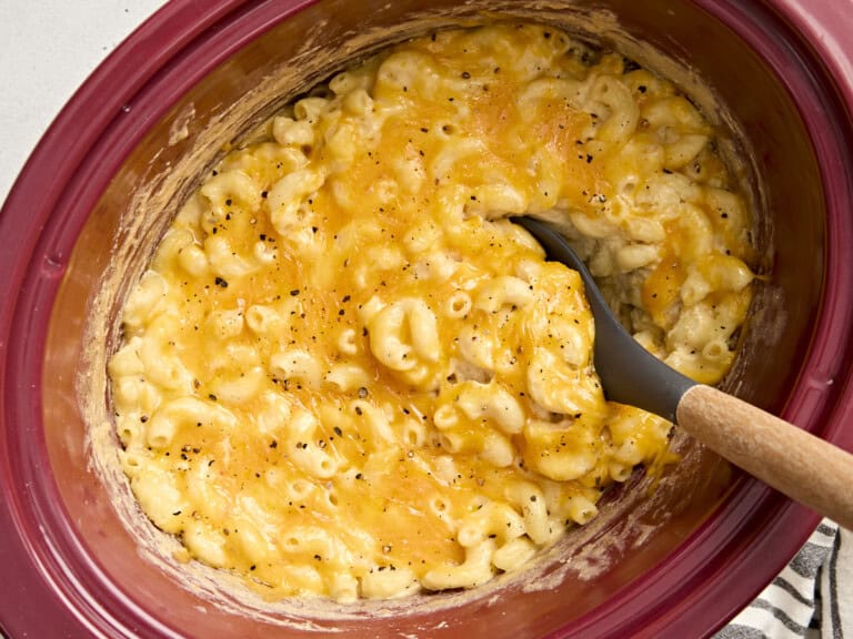 Overhead view of crock pot mac and cheese with a large spoon lifting some out.