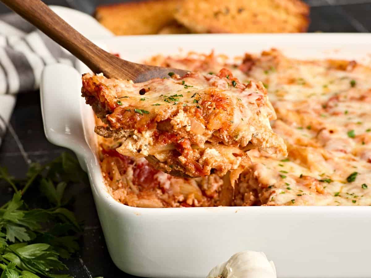 Side view of baked mostaccioli with a serving being lifted out of the pan.