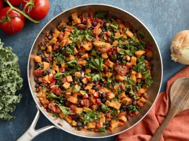 Overhead view of sweet potatoes and black bean skillet with napkin and wooden spoon on the side.