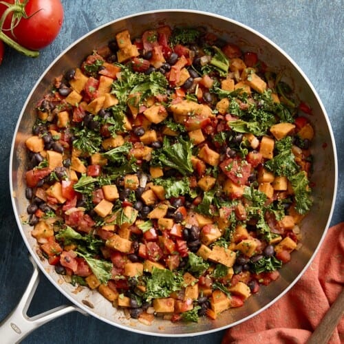 Overhead view of sweet potatoes and black bean skillet with napkin and wooden spoon on the side.