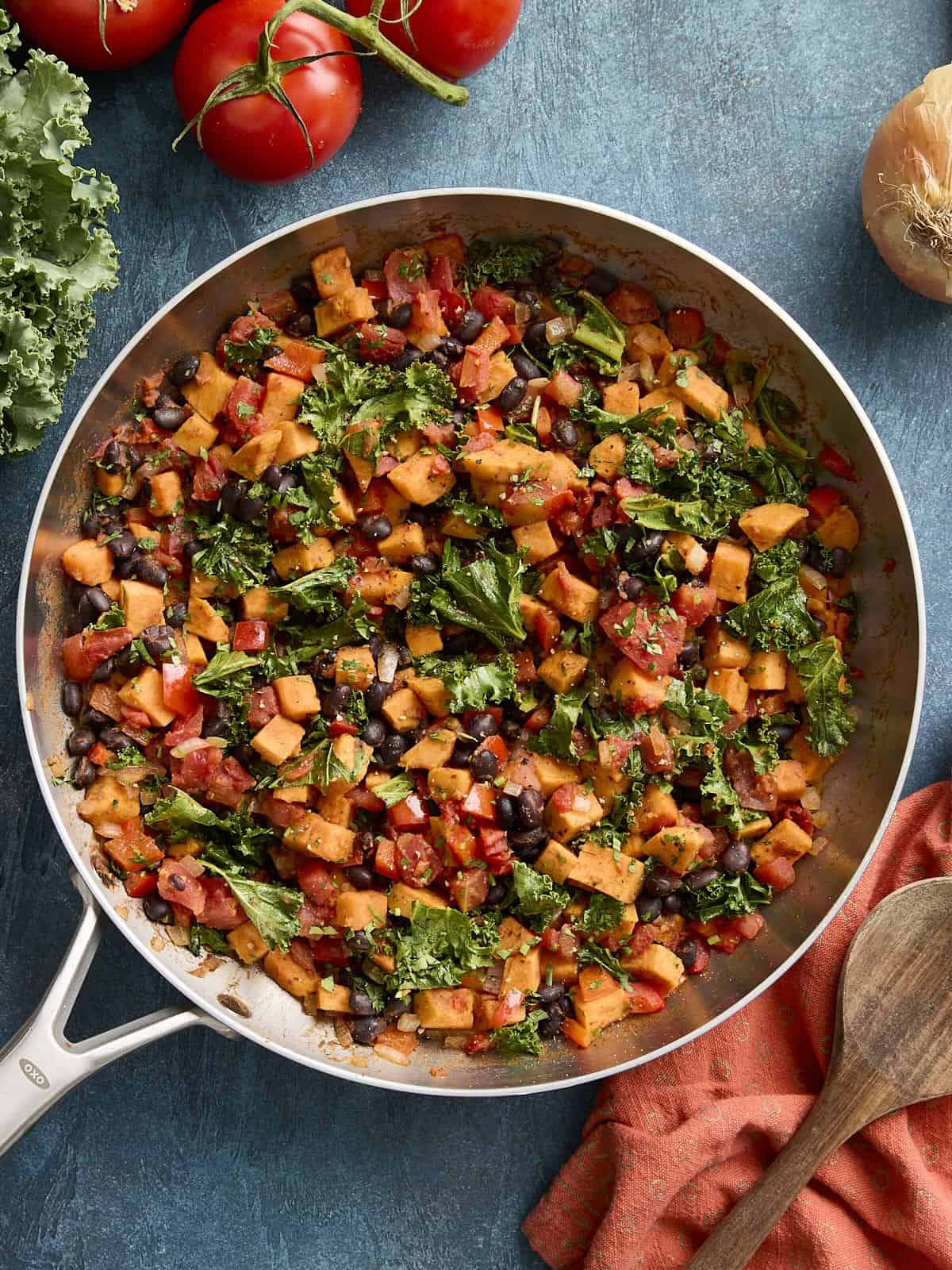 Overhead view of sweet potatoes and black bean skillet with napkin and wooden spoon on the side.