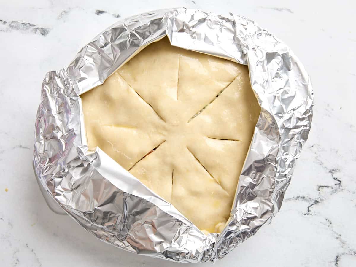 A foil tent added to the top of a turkey pot pie before baking.