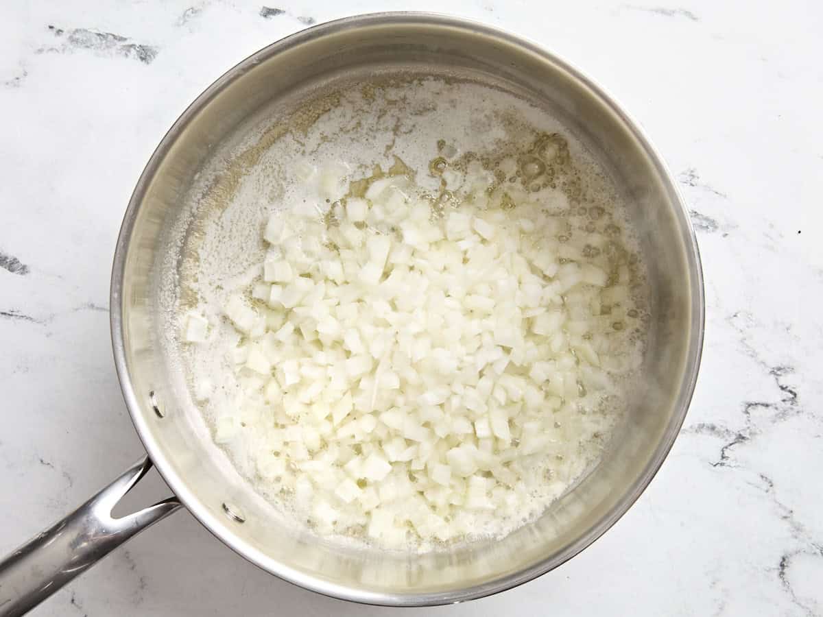 Diced onion cooking in a pan with melted butter.