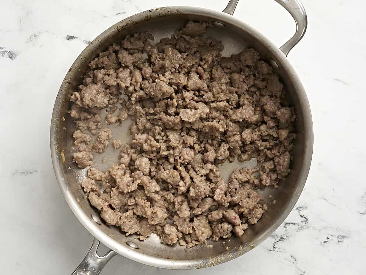 Ground sausage cooking in a skillet.