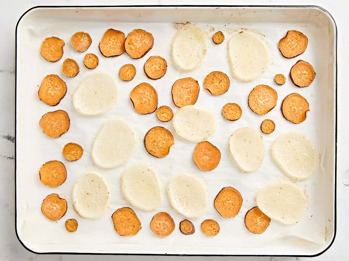 Baked slices of sweet potato and turnip on a baking sheet.