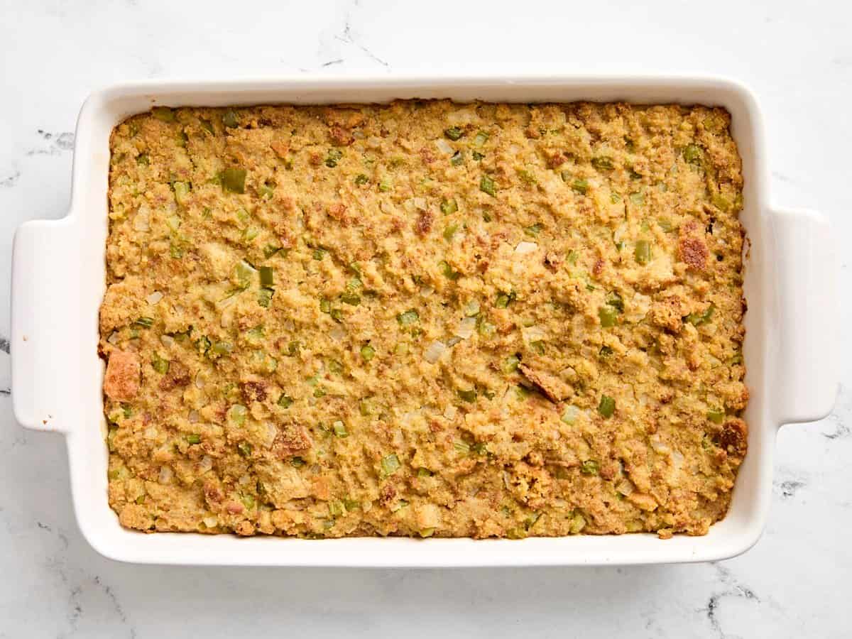 Cooked cornbread dressing in large white baking dish.