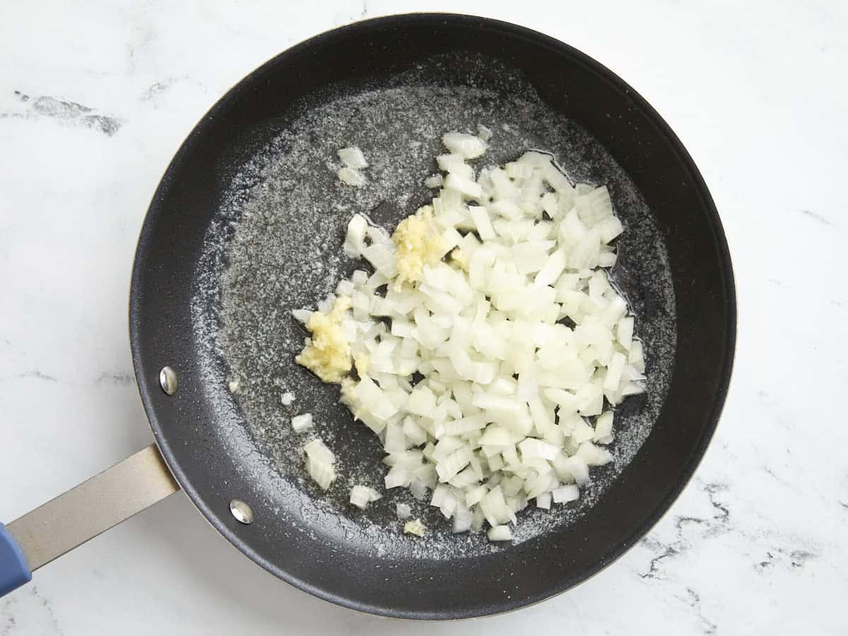 Onions and garlic sauteing in a skillet.