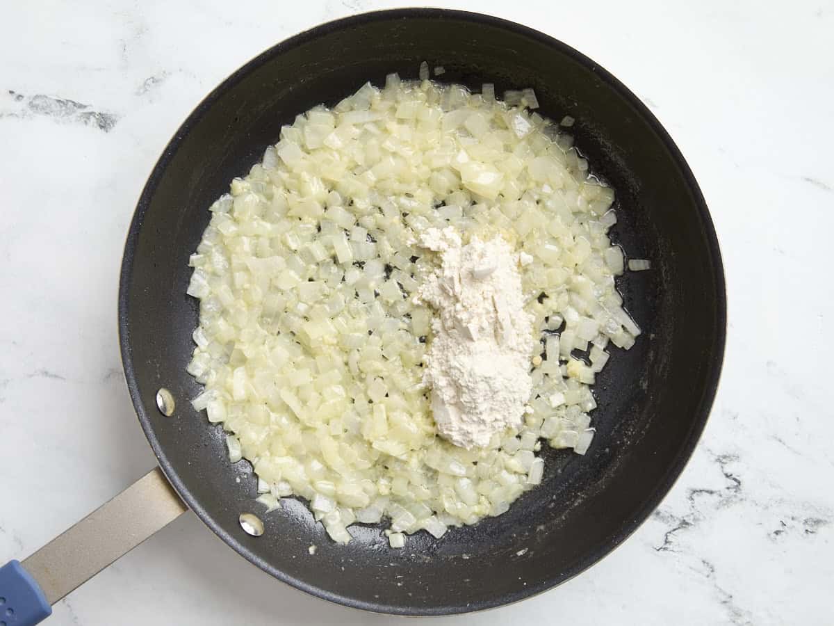 Flour added to diced onions in a skillet.