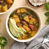 Overhead view of a bowl of butternut squash with black beans soup, topped with avocado.