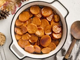 Overhead view of candied yams in a white serving dish.