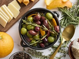 Overhead view of a bowl of marinated olives with fresh herbs.