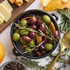 Overhead view of a bowl of marinated olives with fresh herbs.