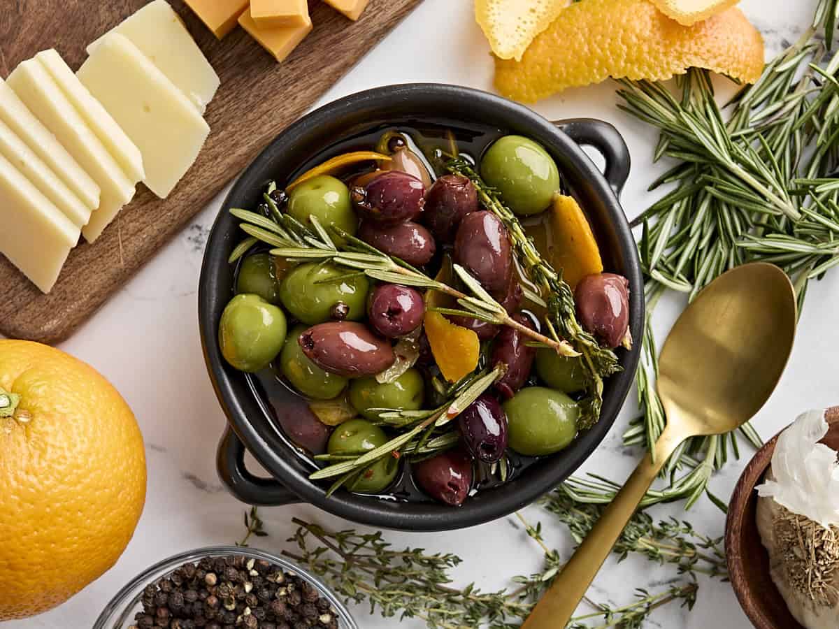 Overhead view of a bowl of marinated olives with fresh herbs.