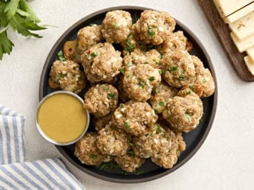 Overhead view of sausage balls on a plate with a side of honey mustard sauce.