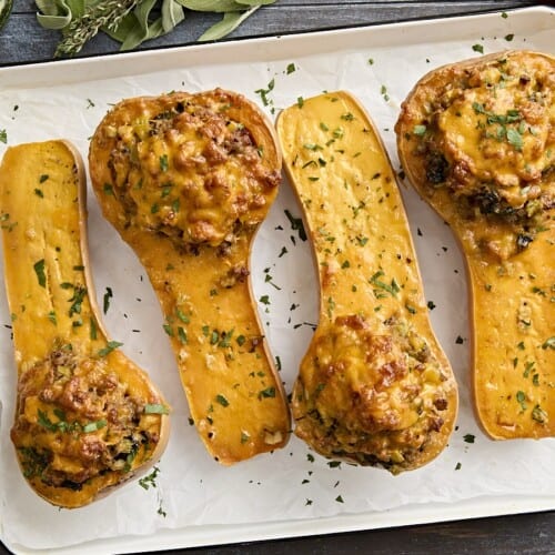 Overhead view of stuffed butternut squash on a baking tray.