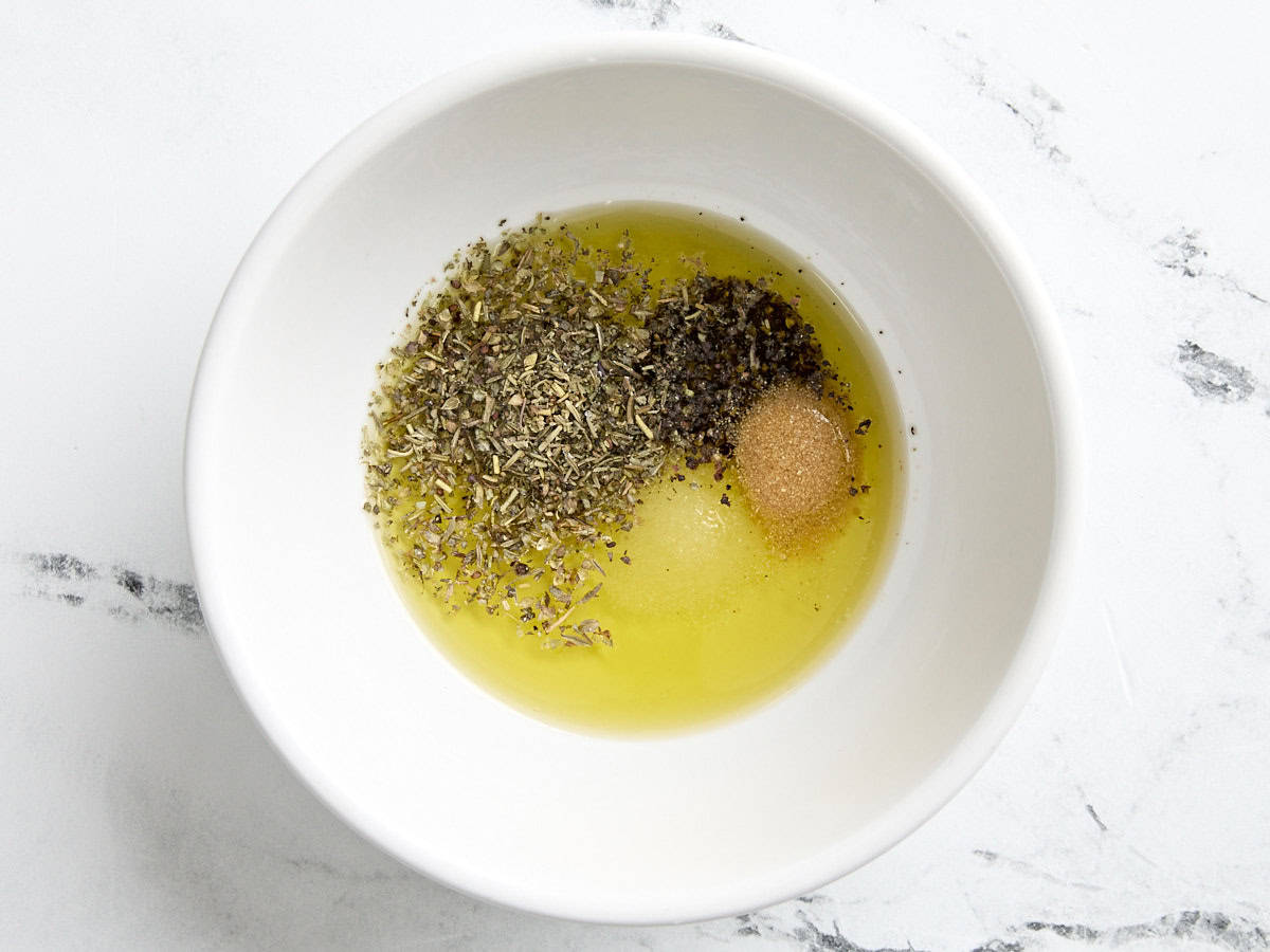 Olive oil and herbs in a mixing bowl.