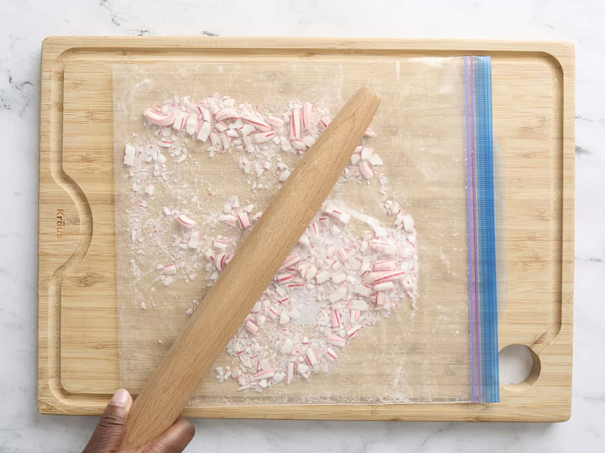 A rolling pin crushing candy canes in a food storage bag.