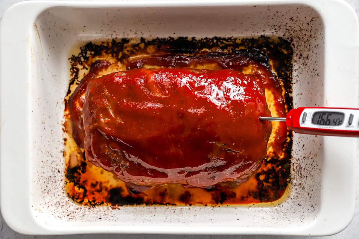 Cooked meatloaf with a meat thermometer sticking out.