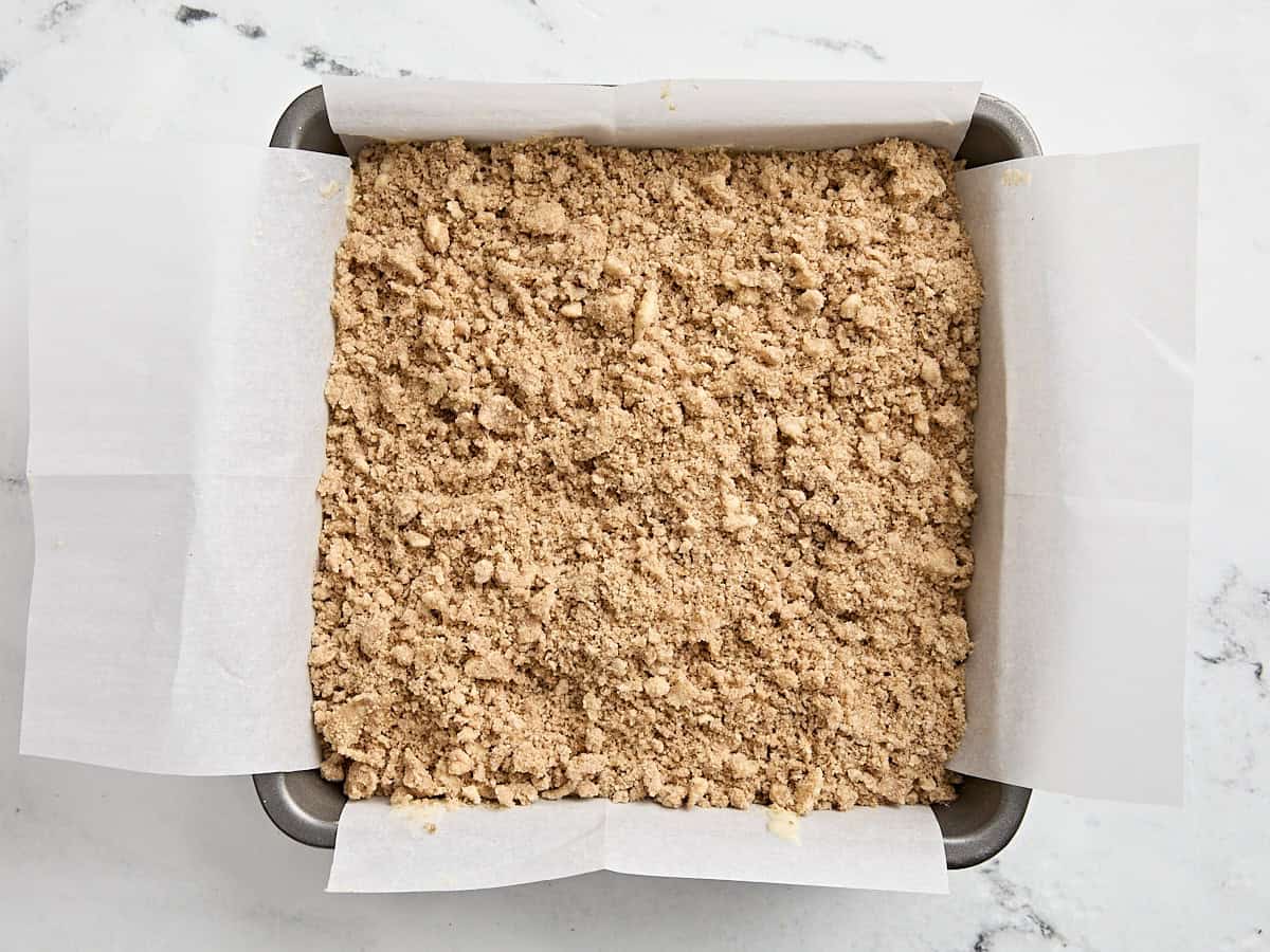 Batter and streusel topping for coffee cake in a parchment lined baking dish.