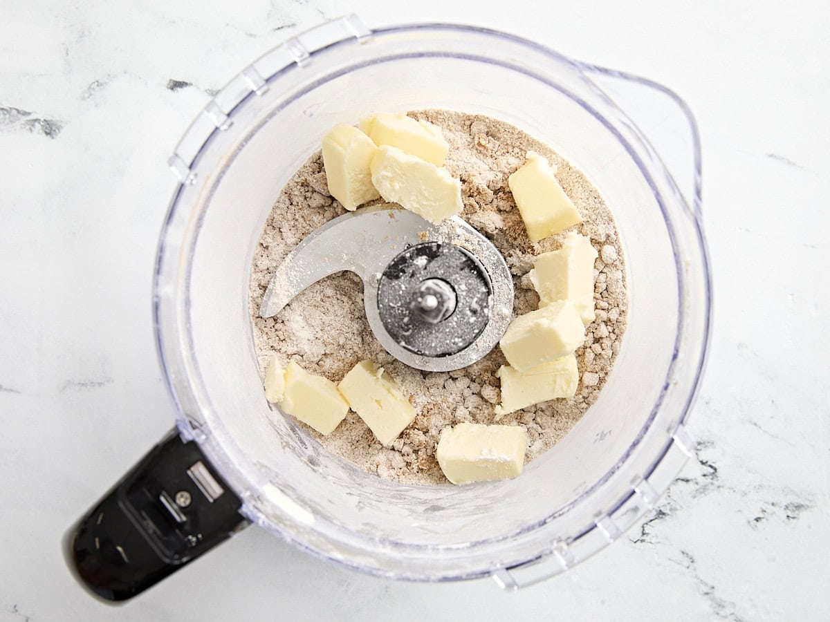 Butter cubes added to sugar streusel topping for coffee cake in a food processor.