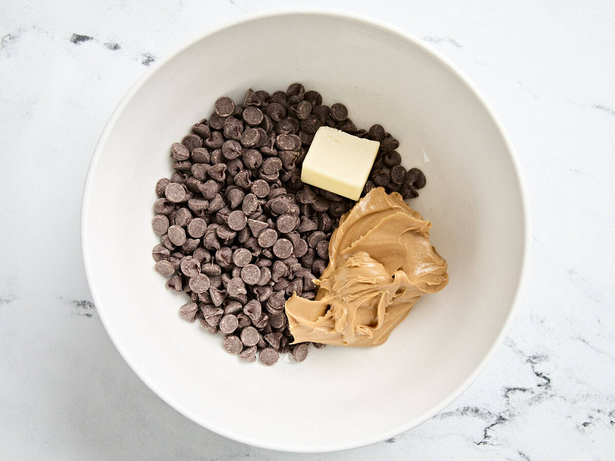 Semisweet chocolate chips, a square of butter, and peanut butter in a bowl.