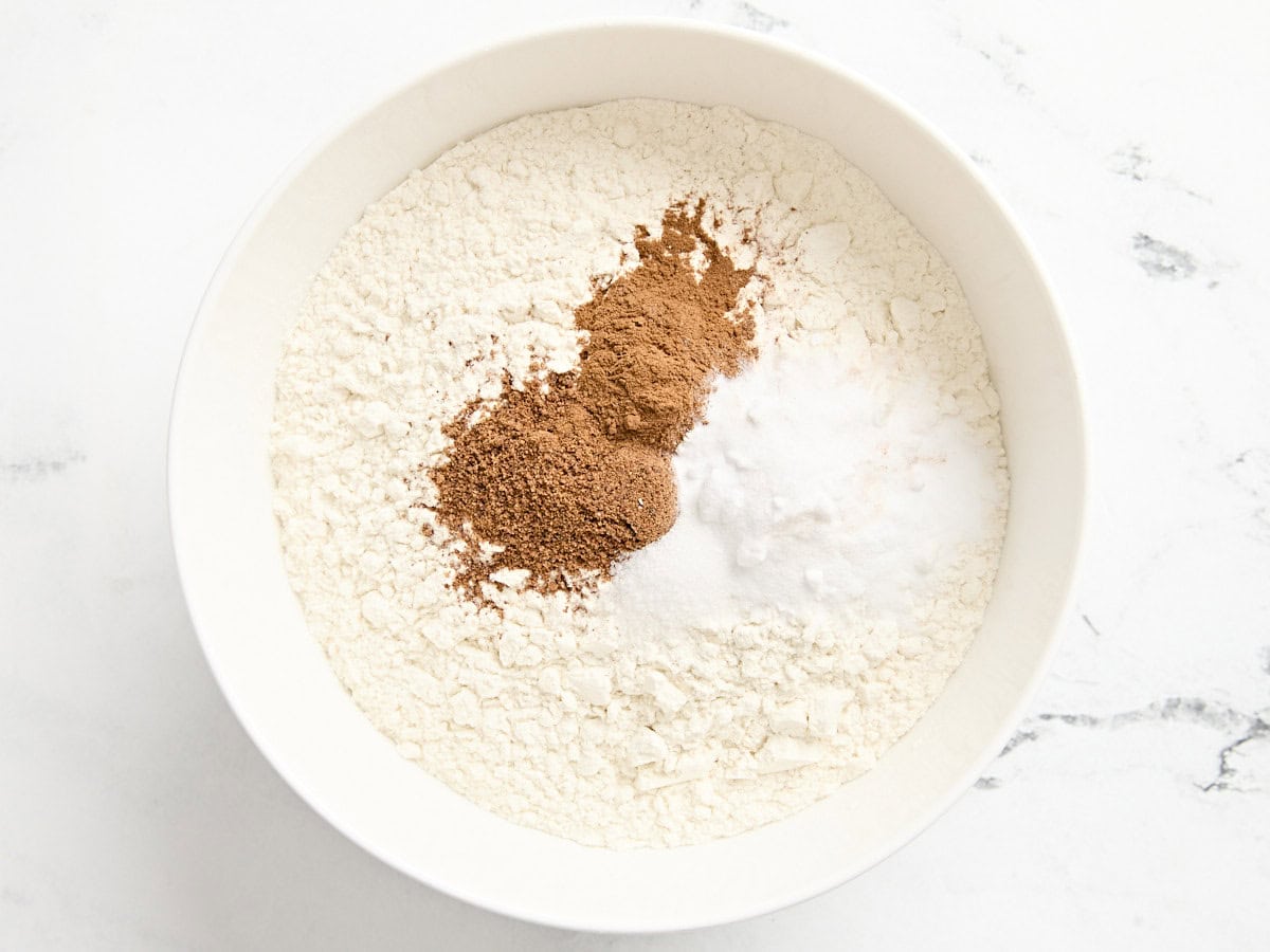 Flour, nutmeg. cinnamon, baking powder and baking soda in a mixing bowl.