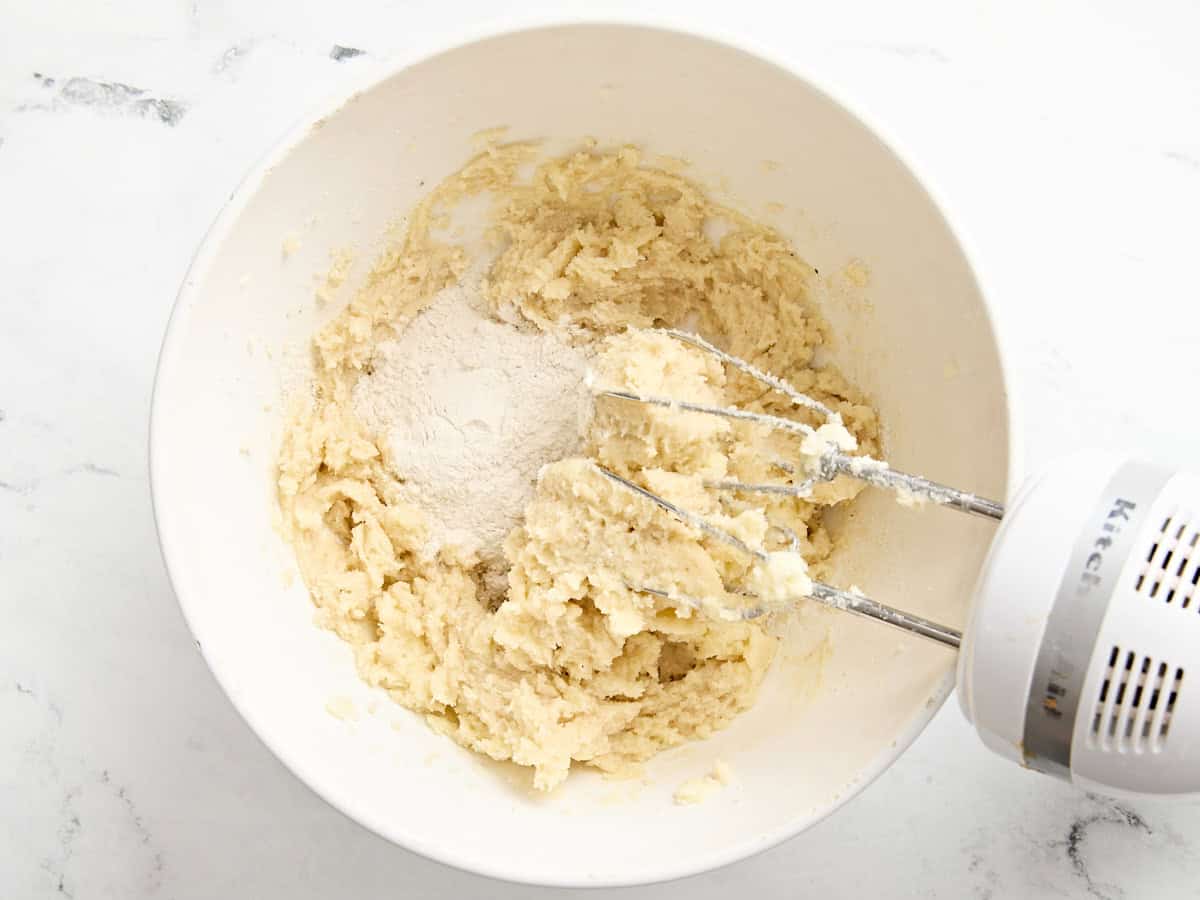 Flour added to creamed butter and sugar in a mixing bowl.