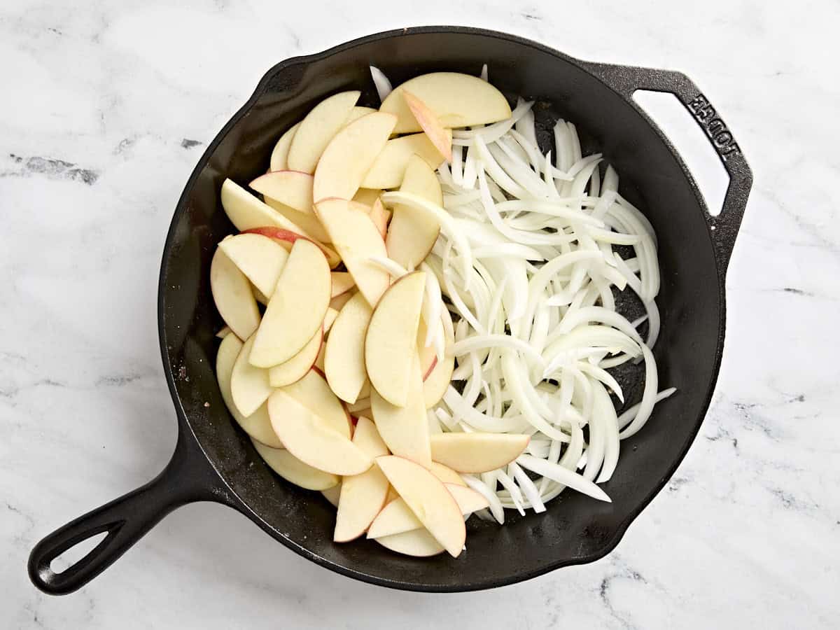 Sliced apples and onions in a skillet.