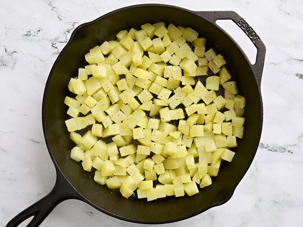 Parboiled diced potatoes adds to a skillet.