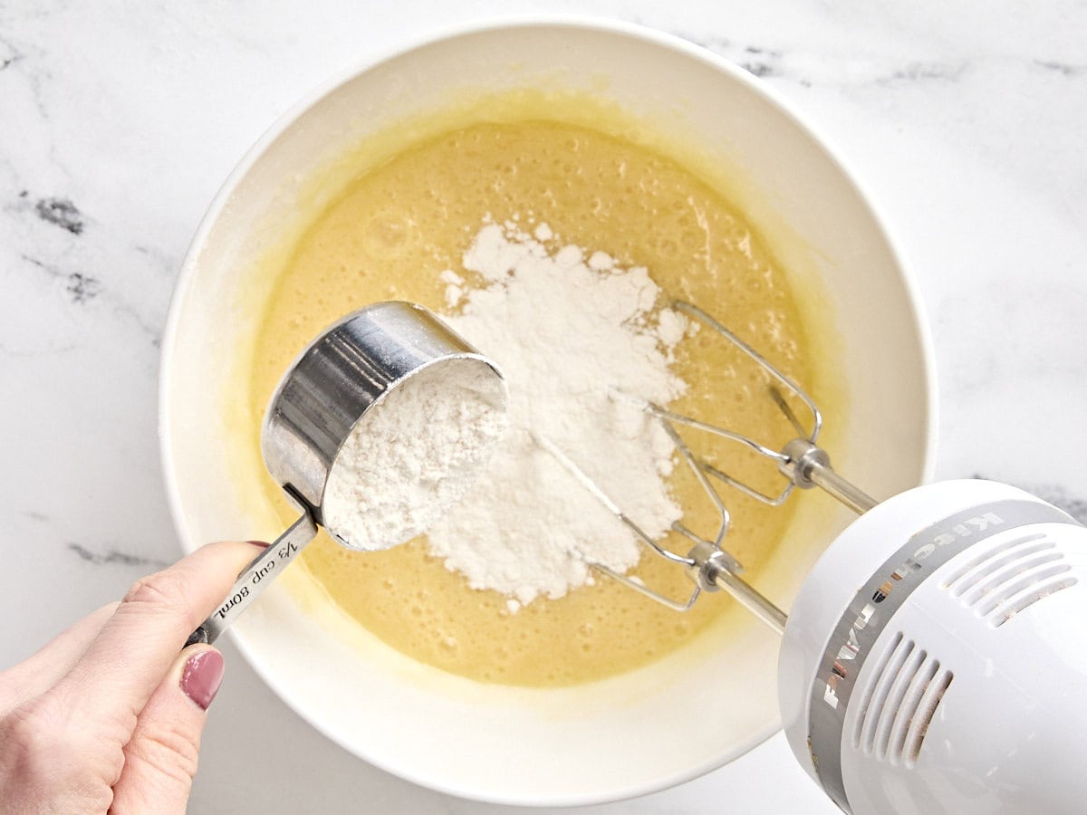 Flour added to wet ingredients for black and white cookies in a bowl.