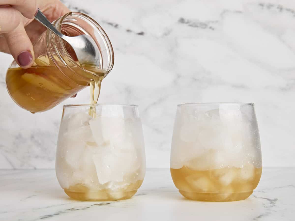 Apple cider shrub being added to a glass of ice.